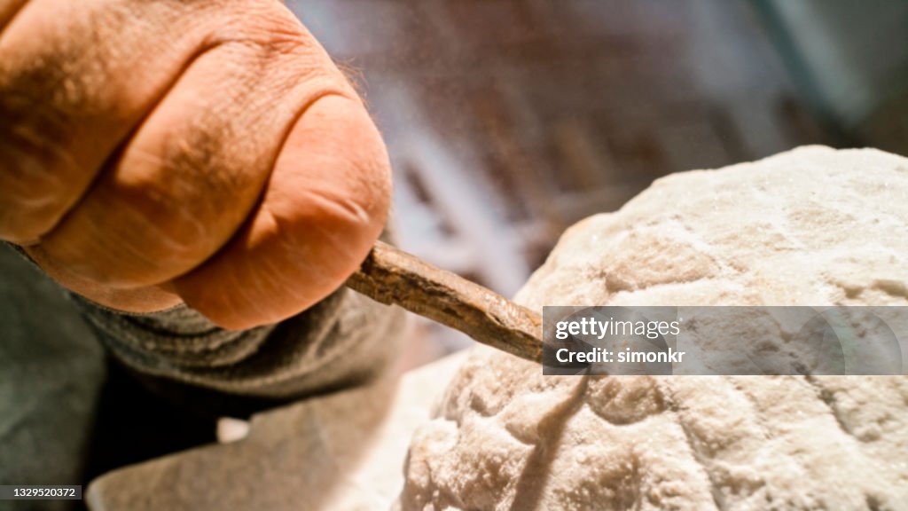 Stonemason chiselling surface of white stone