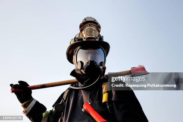 firefighter holding axe. fire prevention and extinguishing concept. - firefighters foto e immagini stock