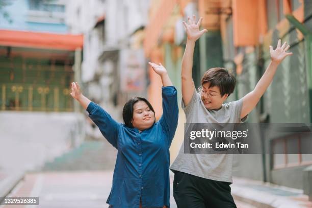 happy asian malay autism down syndrome female  enjoy dancing with her female friend in city street - intellectually disabled stockfoto's en -beelden