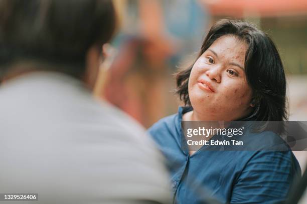 asian malay  autism down syndrome female talking to her friend at city street weekend - autism adult stock pictures, royalty-free photos & images