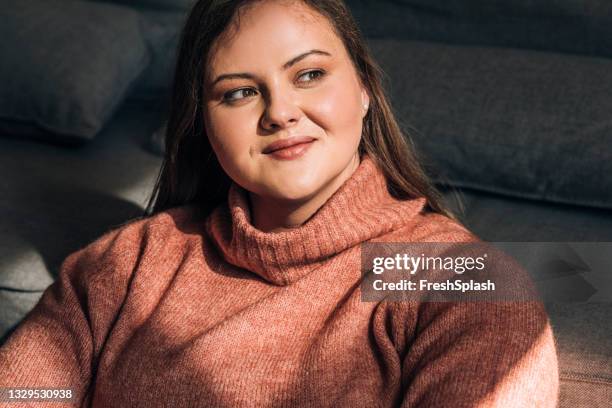 portrait d’une belle femme de taille plus portant un pull à col roulé rouge - mannequin grande taille photos et images de collection