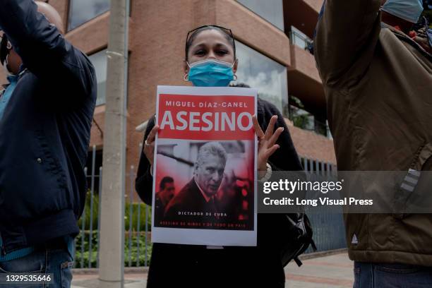 Demonstrator holds a sign with the photo of Cuba's president Miguel Diaz-Cannel that reads 'Murderer, Cuba's dictator' as Cuban residents that live...