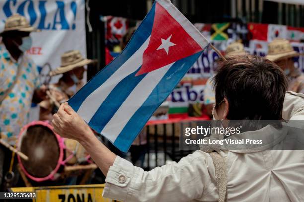 Demonstrator waves a Cuban flag as Cuban residents that live in Colombia protest against the unrest and violence held in the Island against the...