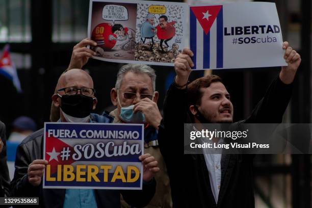 Various demonstrators hold signs in protest against Cuba's violent unrest due to protests as Cuban residents that live in Colombia protest against...