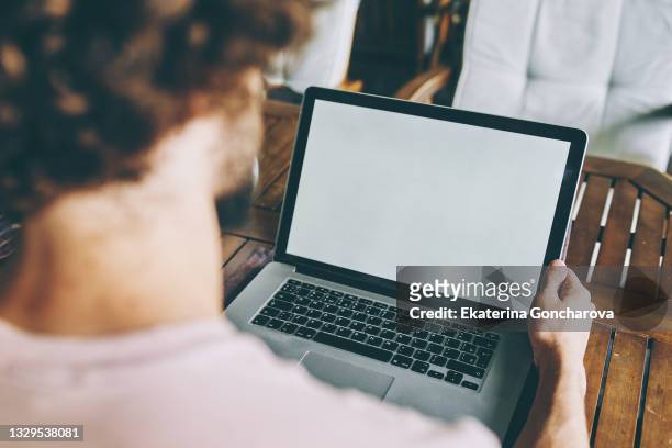 a young man  is working on a laptop with white screen in a cafe - laptop screen stock-fotos und bilder