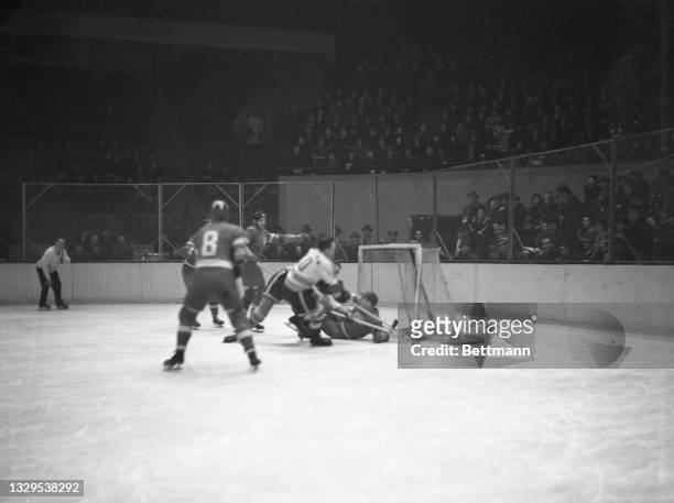 Stewart, of the Americans, falls at the Detroit goal. Goalie Smith, on the ice, prevented the goal, as McDonald, of Detroit, also falls. The New York...