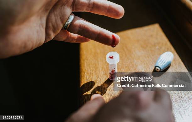 blood is collected in a phial after a finger prick test - lancet arch fotografías e imágenes de stock