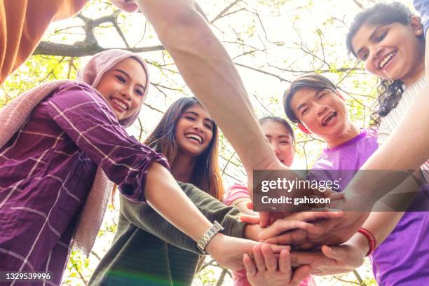 equipo diverso de adultos están de pie en círculo con las manos en un grupo - religion diversity fotografías e imágenes de stock