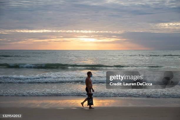 Tourists wear masks as they walk on Patong Beach, Thailand's most popular beach, on July 19, 2021 in Phuket, Thailand. Travelers visit popular...