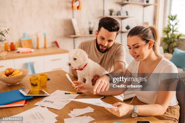 couple checking their finances at home with their dog - life insurance stockfoto's en -beelden