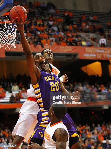Gerardo Suero of the Albany Great Danes takes the ball to the basket as he is blocked by Fab Melo of the Syracuse Orange during the NIT Season...