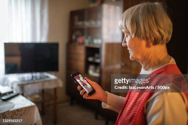 senior woman using mobile phone at home,poland - knowledge is power fotografías e imágenes de stock