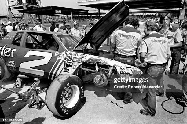 Driver Dale Earnhardt Sr. Sits in his race car while members of his crew work on damage sustained during the running of the 1981 Firecracker 400 race...