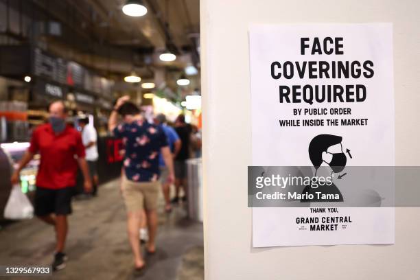 Sign is posted about required face coverings in Grand Central Market on July 19, 2021 in Los Angeles, California. A new mask mandate went into effect...