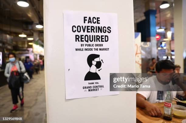 Sign is posted about required face coverings in Grand Central Market on July 19, 2021 in Los Angeles, California. A new mask mandate went into effect...