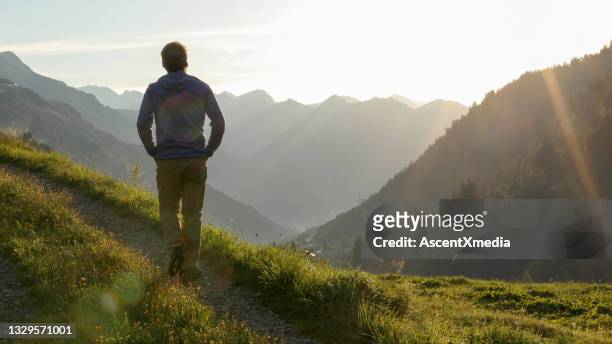 man hikes through grassy meadow in the morning - hands in pockets stock pictures, royalty-free photos & images