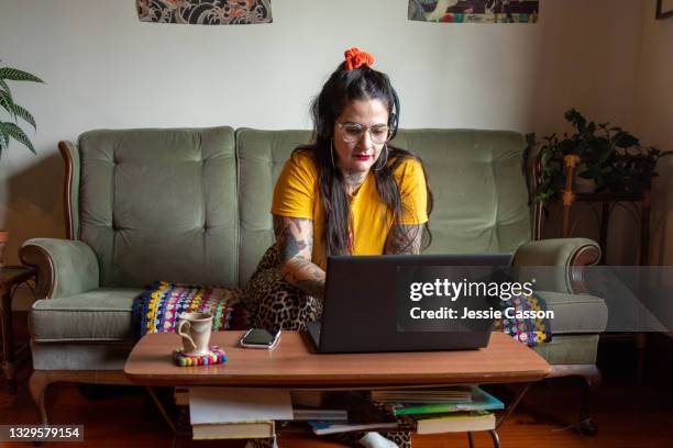 tattooed woman in lounge working on laptop - design laptop woman stock-fotos und bilder