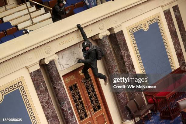 Protester is seen hanging from the balcony in the Senate Chamber on January 06, 2021 in Washington, DC. Congress held a joint session today to ratify...