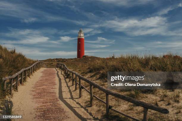 red lighthouse on texel island wooden railing near footpath - friesland netherlands stock pictures, royalty-free photos & images