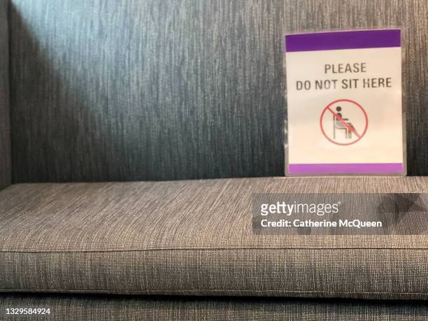 continuing covid-19 reality: sign directing social distancing on sofa in waiting room - restricted area sign stock pictures, royalty-free photos & images