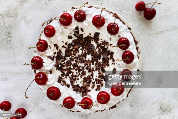 image of black forest gateau with piped whipped cream rosettes topped with morello cherries, luxury chocolate cake frosted with whipped cream and covered with chocolate shavings, marble effect background, elevated view - gateaux bildbanksfoton och bilder