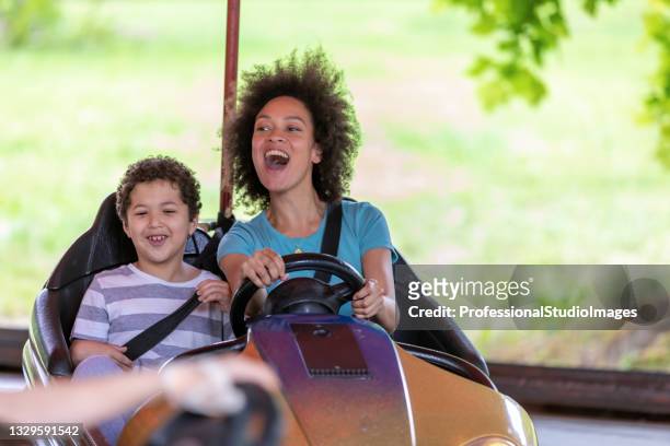 eine afroamerikanische familie genießt es, autoscooter zu fahren im vergnügungspark. - fahrzeug fahren stock-fotos und bilder