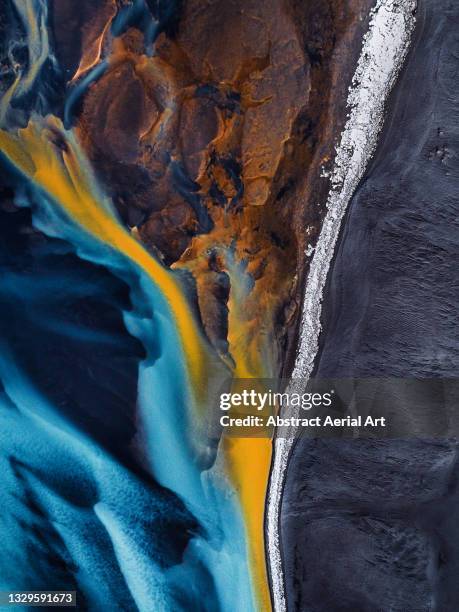 aerial shot looking down on a braided river at the edge of a black sand beach, iceland - estuario fotografías e imágenes de stock