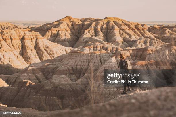 photographe debout devant la vaste badland du canyon dans une lumière dorée - dakota du sud photos et images de collection