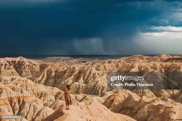 woman in dress overlooking panoramic views of desert badlands during a thunderstorm - philip browne stock pictures, royalty-free photos & images