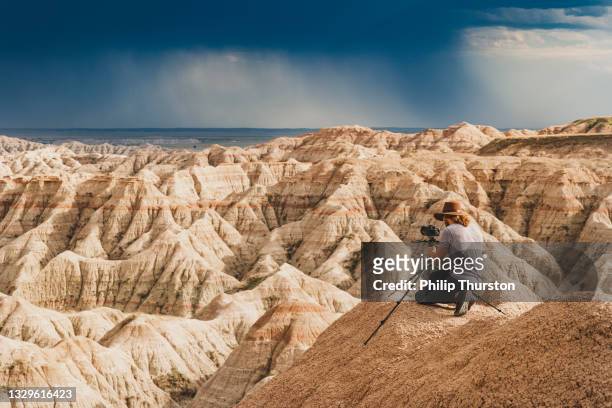 man photographing brightly lit canyons in front of a dark stormy sky - brightly lit imagens e fotografias de stock