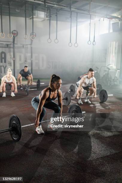 group of athletic people exercising with barbells during cross training in a gym. - squat exercise man stock pictures, royalty-free photos & images