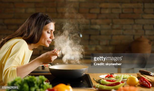 台所で食事を作りながら楽しむ若い女性。 - 女性　料理 ストックフォトと画像