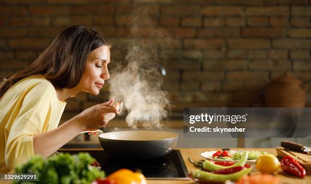 jovem desfrutando enquanto cozinhava refeição na cozinha. - cozinha - fotografias e filmes do acervo