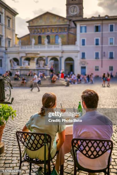 a couple of tourists admires the artistic beauties of santa maria in trastevere in the heart of rome - filmtitel stockfoto's en -beelden