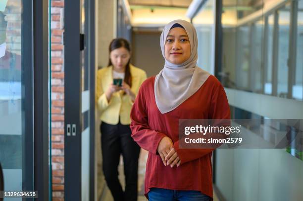 schönes asiatisches modernes muslimisches geschäftsfrauenporträt im bürokorridor - work gender equality stock-fotos und bilder