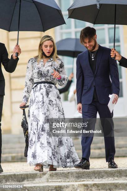 Guest wears a white with black constellations print pattern long dress from Dior with V-neck / puffy sleeves / flowing long skirt, a gold pearls...