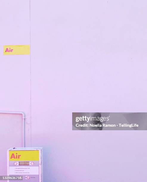 a pink wall, a sign with the word air and a air pump - luftpumpe stock-fotos und bilder