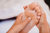 Close up of foot reflexology showing female hands on a acupressure point on the plantar surface