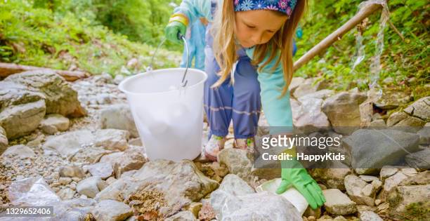 girl picking up plastic rubbish in forest - only girls stock pictures, royalty-free photos & images