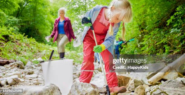 girl collecting plastic rubbish in the forest. - only girls stock pictures, royalty-free photos & images