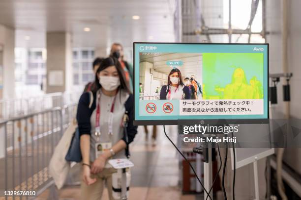 Journalists get their temperature checked as they enter the IBC/MPC Tokyo International Exhibition Centre next to sign to keep a distance ahead of...