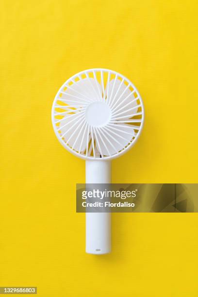 white plastic hand fan on a yellow background - electric fan stock pictures, royalty-free photos & images