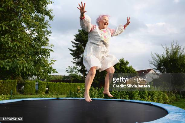 ältere frau mit übergewicht springt auf trampolin - trampoline equipment stock-fotos und bilder