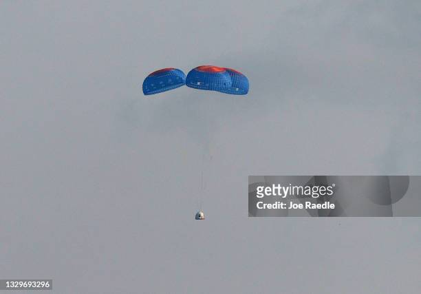 Blue Origin’s New Shepard crew capsule descends on the end of its parachute system carrying Jeff Bezos along with his brother Mark Bezos, 18-year-old...