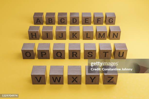 rows of wooden text alphabet block on yellow background - jonny k stock pictures, royalty-free photos & images