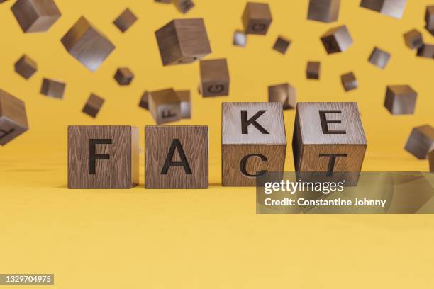 fake or fact concepts with wooden text alphabet block on yellow background - imitatie stockfoto's en -beelden