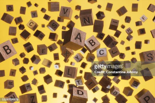 abstract background of wooden text alphabet block floating in the air on yellow background - abc blocks stock pictures, royalty-free photos & images