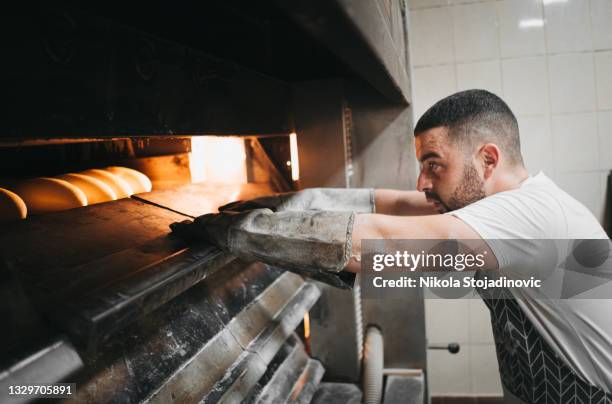 baker in his bakery baking bread - oven stockfoto's en -beelden