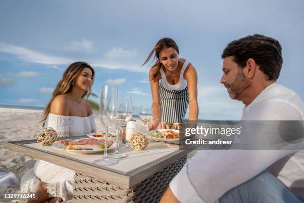 waitress serving food to a couple on a romantic dinner at the beach - service anniversary stock pictures, royalty-free photos & images