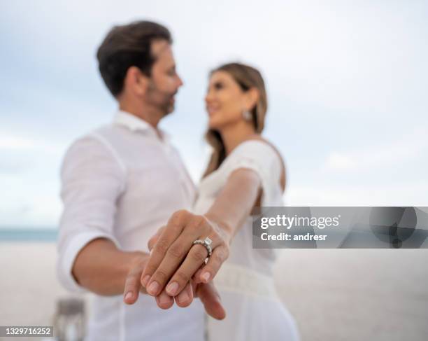 couple getting engaged at the beach and showing the ring to the camera - 訂婚戒指 個照片及圖片檔